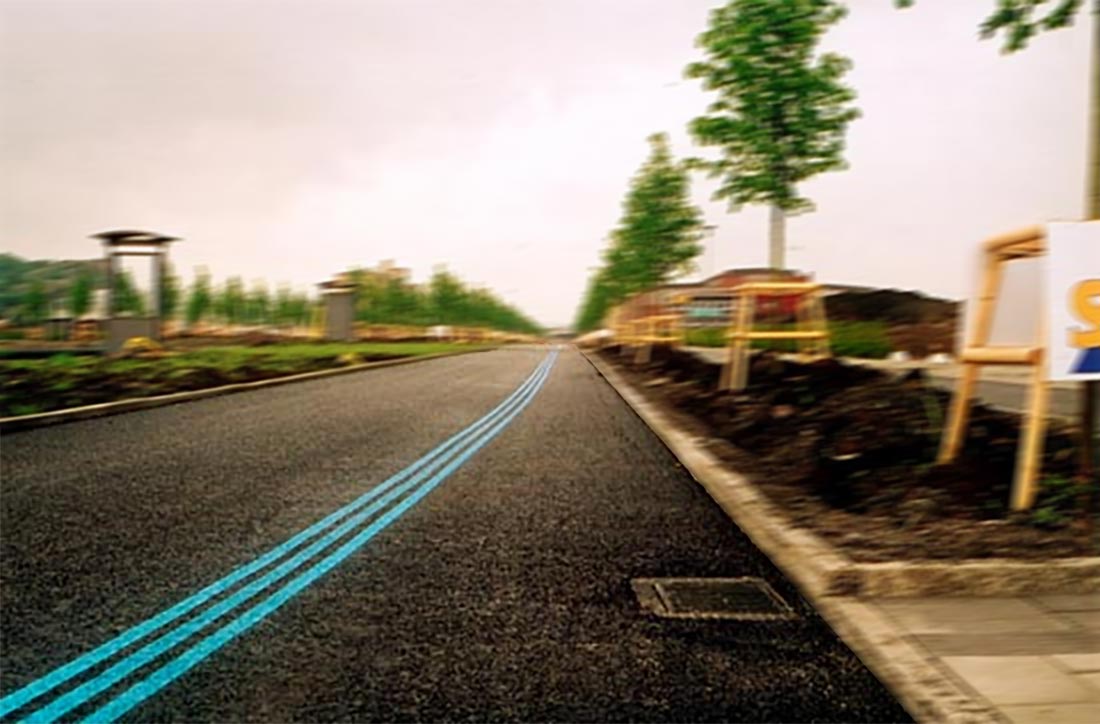 Bild tagen i hög fart som visar blå linjemarkeringar på asfaltsväg